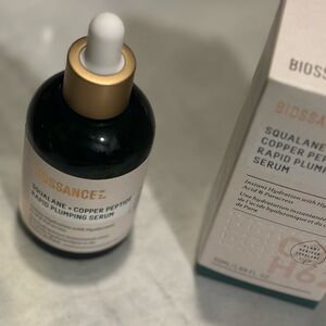 Biossance Gold and White Serum in a Round Glass Bottle
